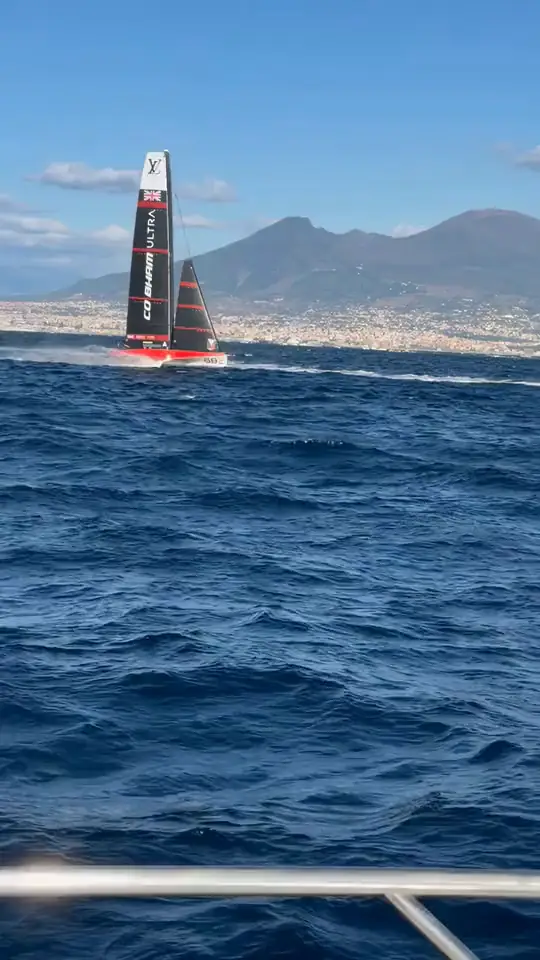 Una barca dell'America's Cup in regata nel golfo di Napoli, col Vesuvio sullo sfondo