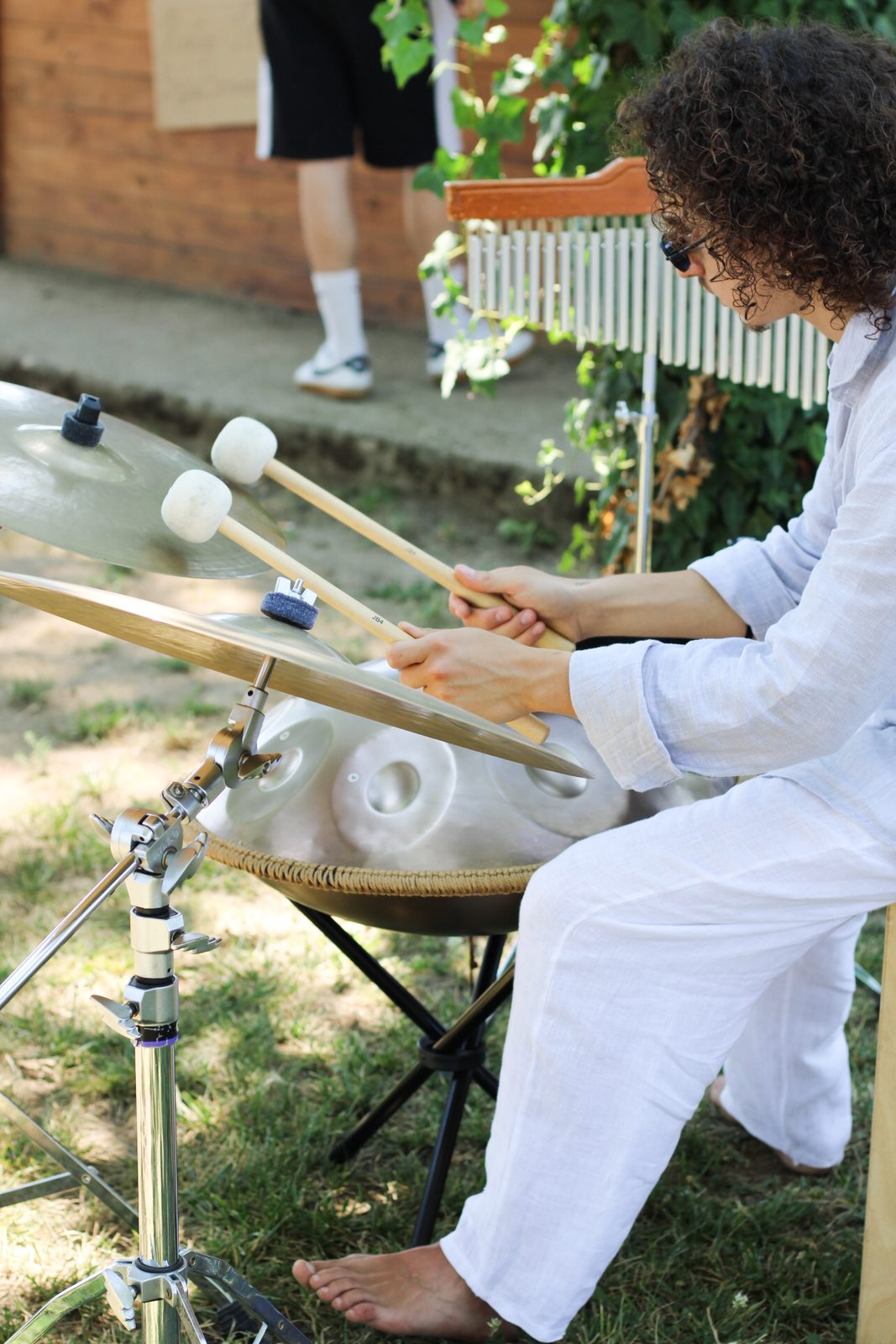 Musicista con handpan e piatti in giardino