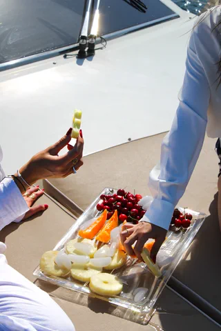 Mani che servono un vassoio di frutta fresca sul ponte, al sole