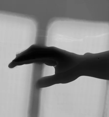 Una mano in ombra premuta contro una superficie traslucida