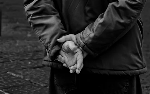Le mani di un uomo intrecciate dietro la schiena